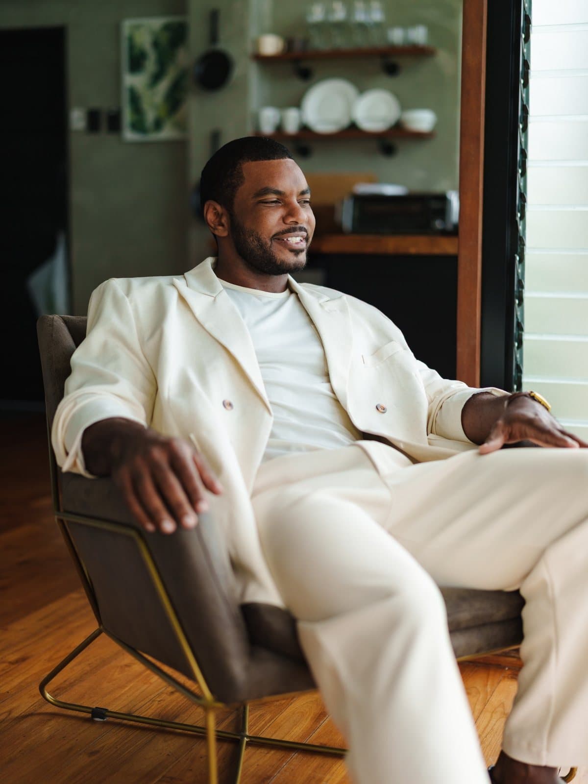 Dr. Edson Breedy seated in an ivory suit, looking out toward the window