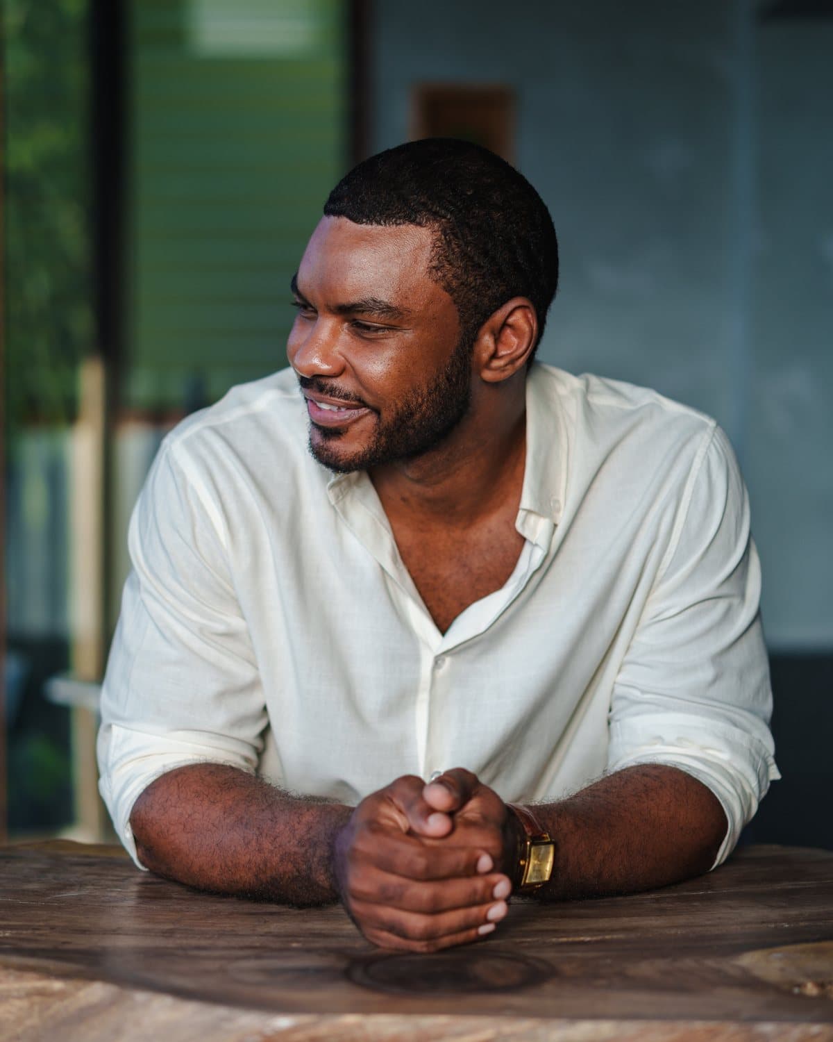 Dr. Edson Breedy at a table in a white linen shirt, looking to the side